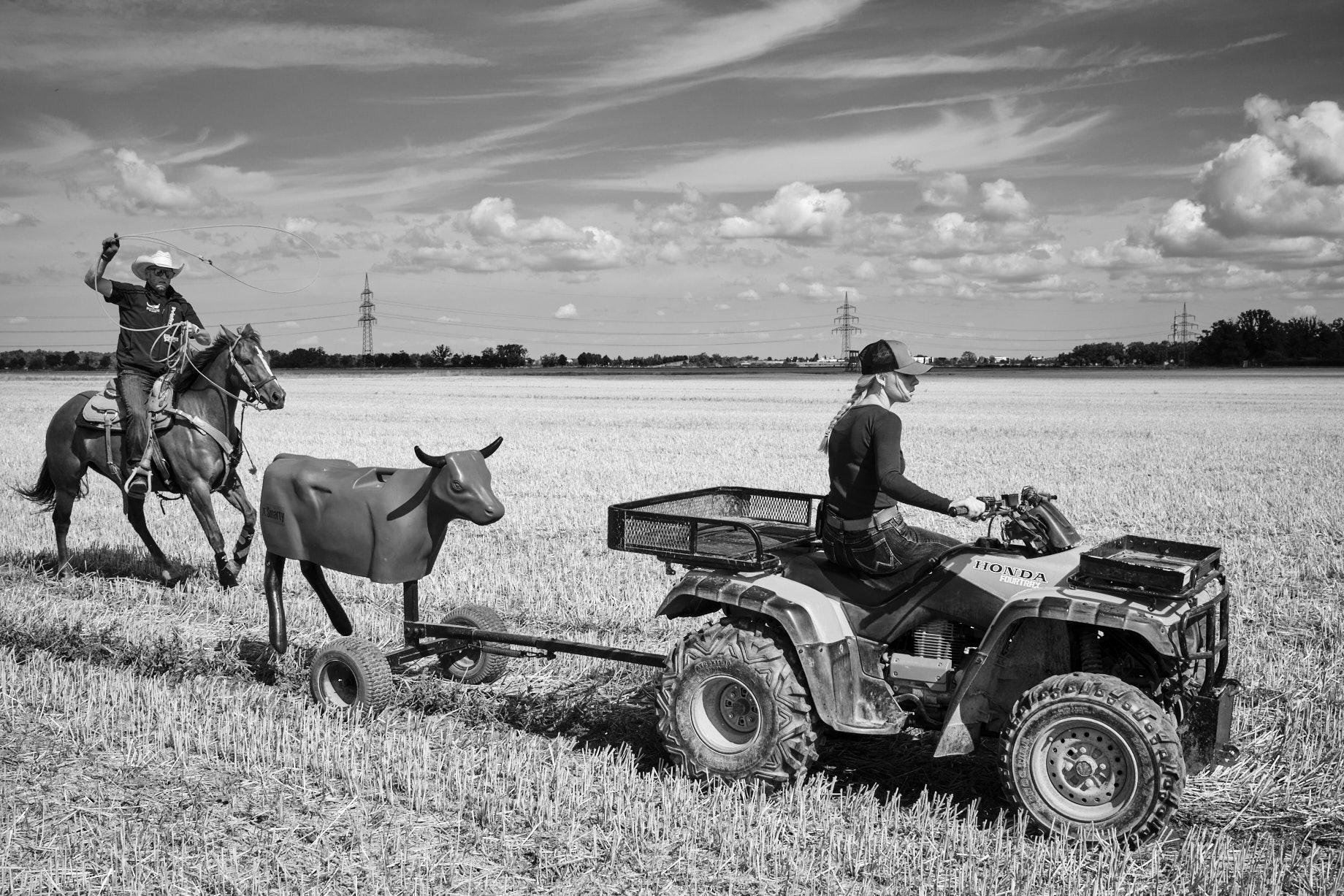 Junge Frau auf Quad zieht eine Klabattrappe, die ein Reiter lassoschwingend verfolgt. - Foto: Thomas Steinberg