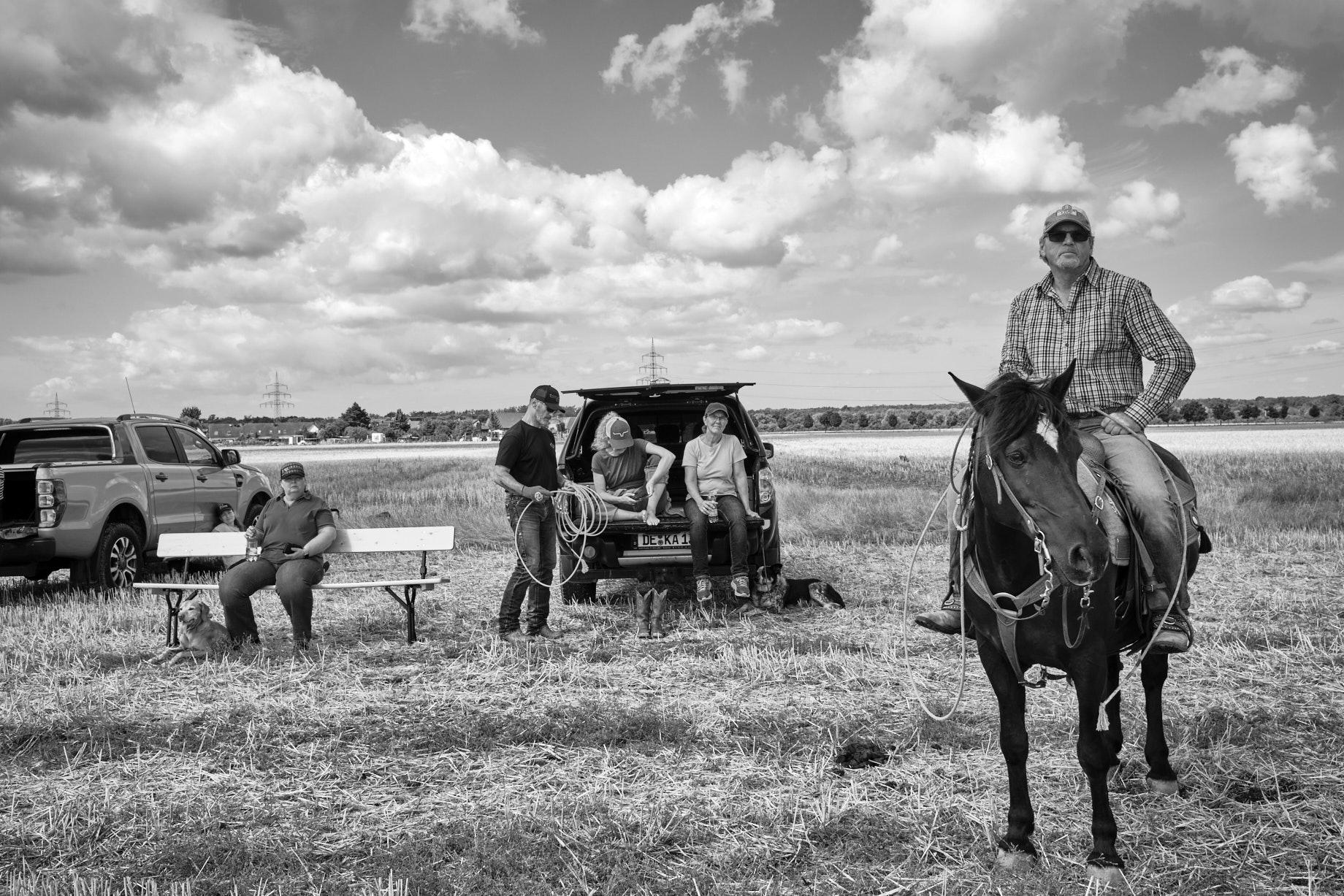 Mann auf Pferd, hinter ihm einige Frauen, die auf der Ladeklappe eines Pick-Ups sitzen - Foto: Thomas Steinberg