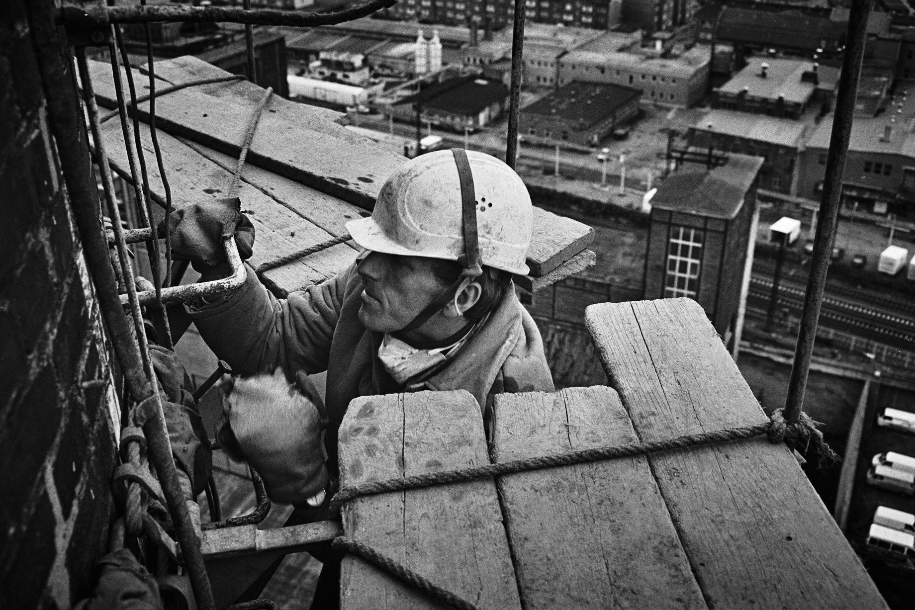Ein Abbrucharbeiter steigt auf einen Schornstein. - Foto: Thomas Steinberg