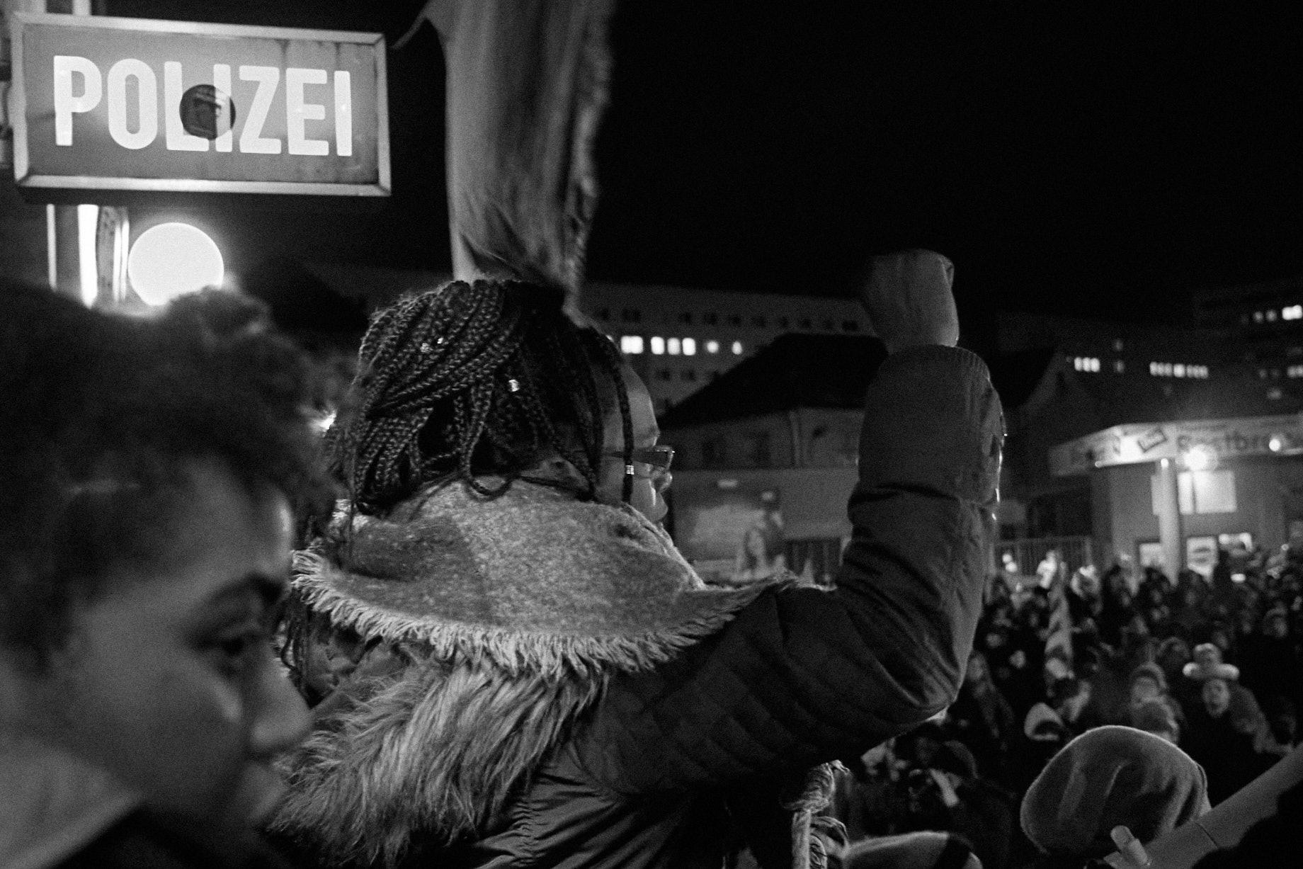 Eine Frau demonstriert mit anderen Menschen vor dem Polizeirevier Dessau. - Foto: Thomas Steinberg